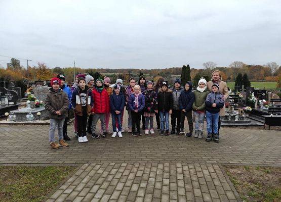 Zdjęcie grupowe uczniów z wychowawcą na cmentarzu w Łebieniu