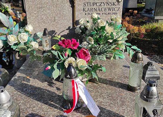 Na nagrobku stoją znicze i kwiaty