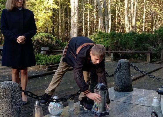 Uczeń ustawia znicz z napisem Szkoła Pamięta