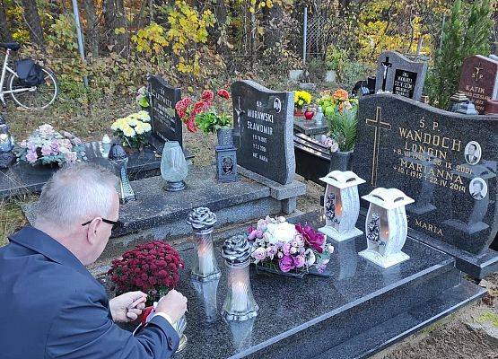 Dyrektor ustawia na nagrobku znicz z napisem szkoła Pamięta