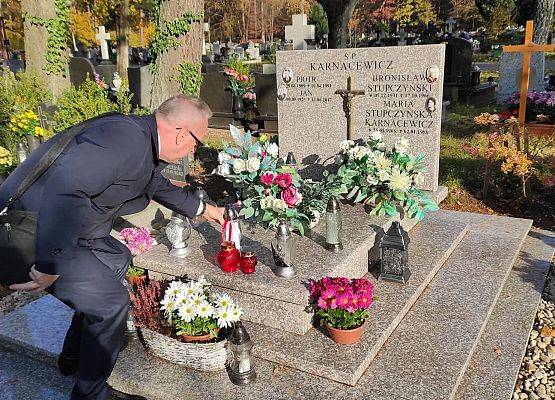 Dyrektor ustawia na nagrobku znicz z napisem szkoła Pamięta