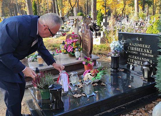 Dyrektor ustawia na nagrobku znicz z napisem szkoła Pamięta