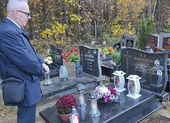 Dyrektor ustawia na nagrobku znicz z napisem szkoła Pamięta