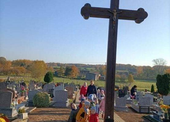 Przedszkolaki przy stoją przy krzyżu na cmentarzu w Łebieniu