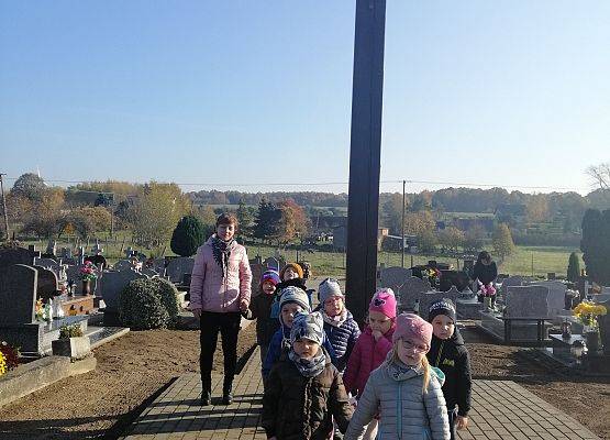 Przedszkolaki idą aleją na cmentarzu w Łebieniu