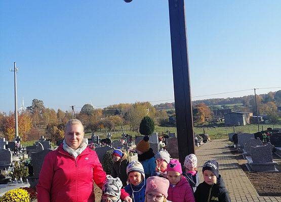 Przedszkolaki idą aleją na cmentarzu w Łebieniu