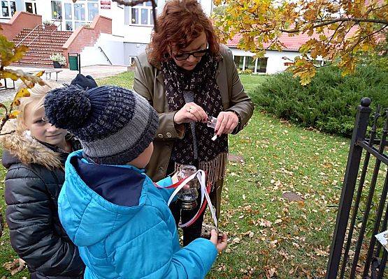 Nauczycielka zapala znicz z napisem Szkoła Pamięta przed "Dębem Katyńskim"