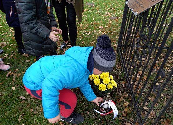 Uczeń ustawia znicz z napisem Szkoła Pamięta przed "Dębem Katyńskim"