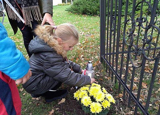 Uczennica ustawia znicz z napisem Szkoła Pamięta przed "Dębem Katyńskim"