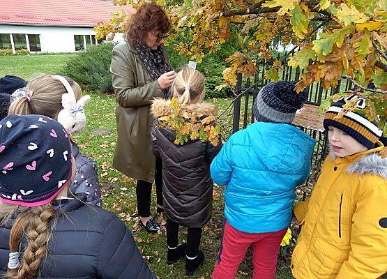 Nauczycielka zapala znicz z napisem Szkoła Pamięta przed "Dębem Katyńskim"