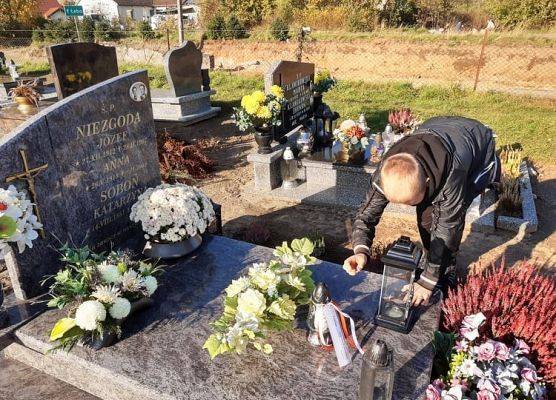 Uczeń stawia na nagrobku znicz z napisem Szkoła Pamięta