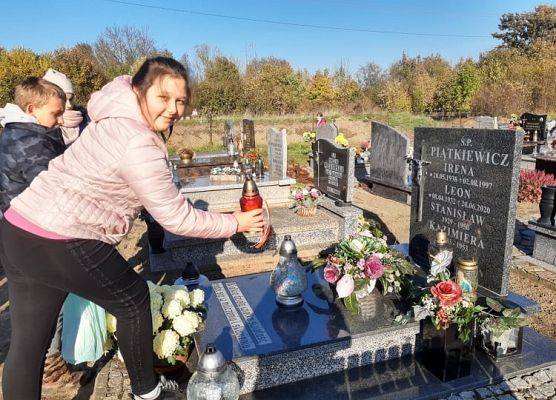 Uczennica stawia znicz na nagrobku