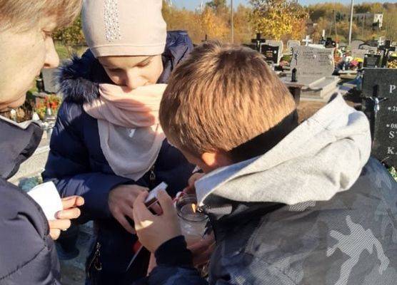 Uczniowie zapalają znicz