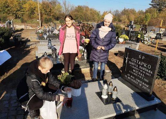 Uczeń stawia na nagrobku znicz z napisem Szkoła Pamięta