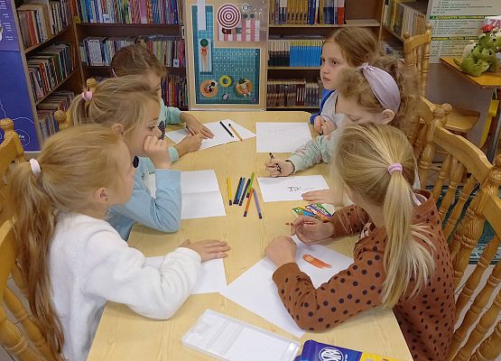 Dziewczynki siedzą przy stole i rysują