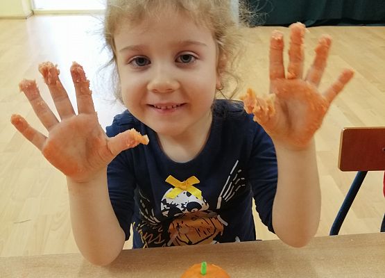 Dziewczynka  prezentuje wykonaną przez siebie dynię