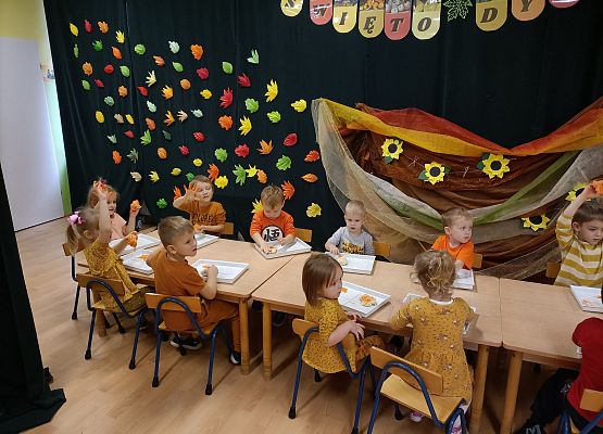 Dzieci siedzą przy stoliku i wykonują prace plastyczne