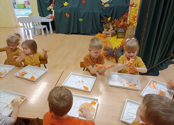 Dzieci siedzą przy stoliku i wykonują prace plastyczne