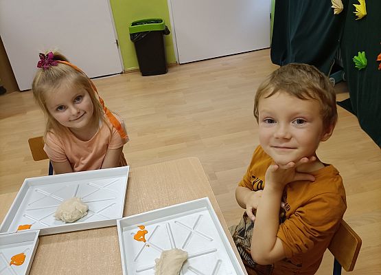 Dzieci siedzą przy stoliku i wykonują prace plastyczne