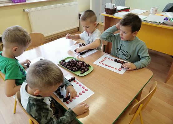 Chłopcy układają różne kształty z kasztanów