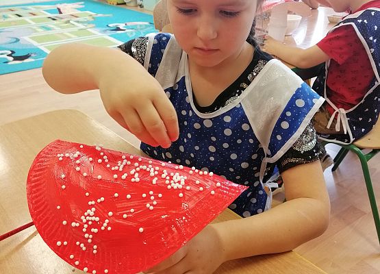 Dziewczynka posypuje białymi kulkami muchomora