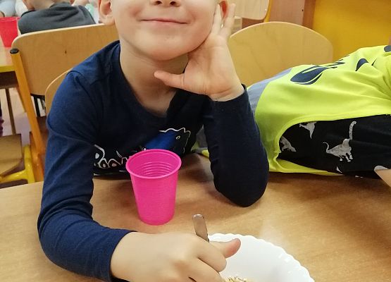 Chłopiec za pomocą pęsety przenosi groszki z miski do kubka