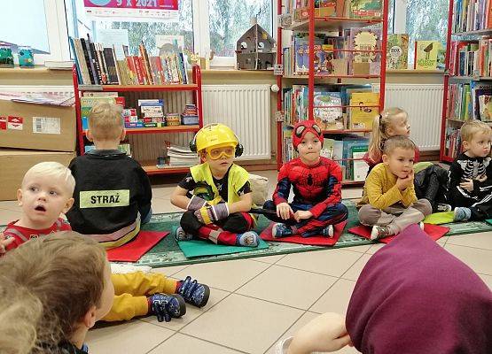 Dzieci siedzą w bibliotece i słuchają bajki