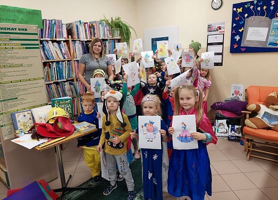 Grupa dzieci pokazuje swoje prace plastyczne