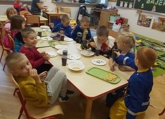 Dzieci siedzą przy stolikach