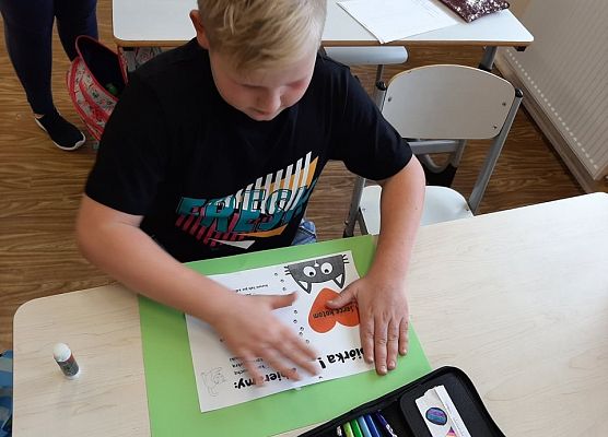 Uczeń wykonuje plakat na temat zbiórki dla kotów