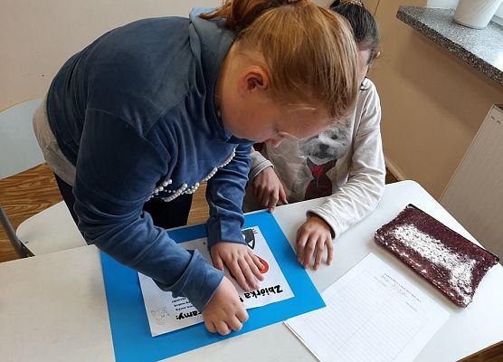 Dziewczynka skleja arkusze papieru