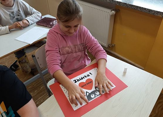 Uczennica wykonuje plakat na temat zbiórki dla kotów