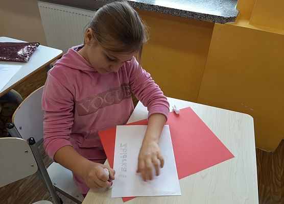 Dziewczynka smaruje klejem arkusz papieru