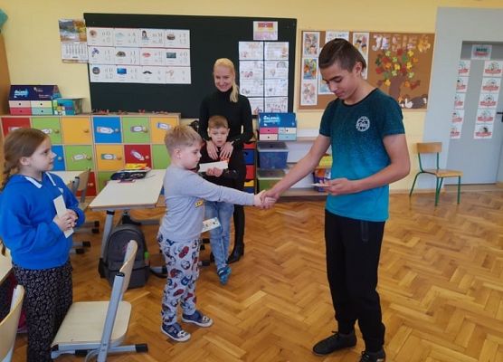 Przedstawiciel samorządu wręcza uczniowi zakładkę do książki