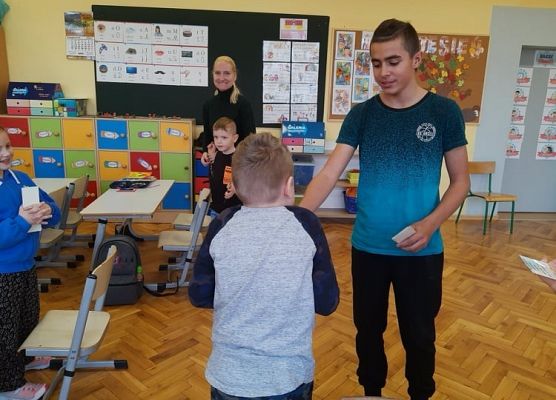 Przedstawiciel samorządu wręcza uczniowi zakładkę do książki