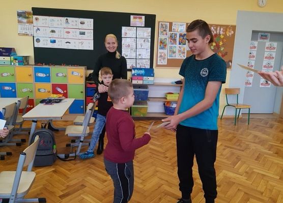 Przedstawiciel samorządu wręcza uczniowi zakładkę do książki