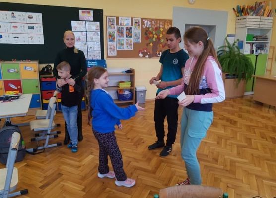 Przedstawiciel samorządu wręcza uczniowi zakładkę do książki