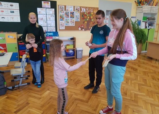 Przedstawiciel samorządu wręcza uczniowi zakładkę do książki