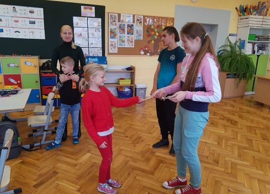 Przedstawiciel samorządu wręcza uczniowi zakładkę do książki