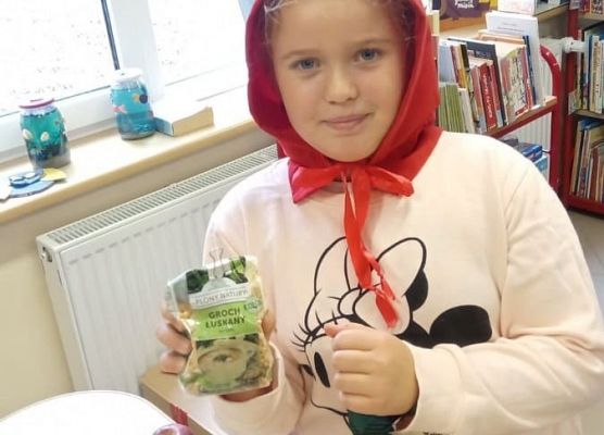 Uczennica w czerwonym kapturku trzyma groch