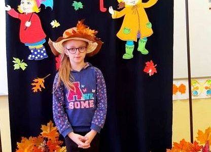 Uczennica stoi i recytuje wiersz o jesieni