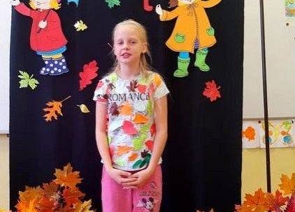 Uczennica stoi i recytuje wiersz o jesieni