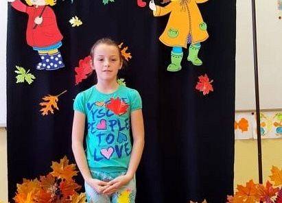 Uczennica stoi i recytuje wiersz o jesieni