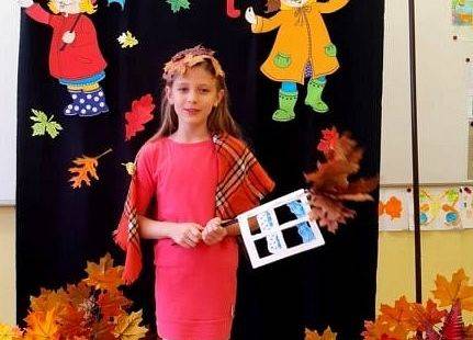 Uczennica stoi i recytuje wiersz o jesieni