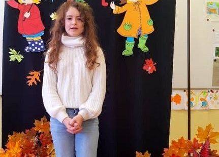 Uczennica stoi i recytuje wiersz o jesieni