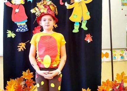 Uczennica stoi i recytuje wiersz o jesieni