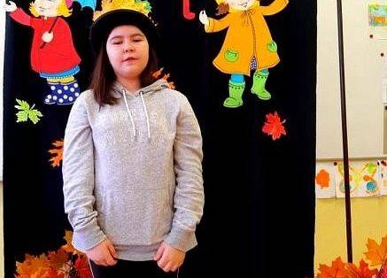 Uczennica stoi i recytuje wiersz o jesieni