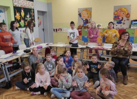 Uczniowie siedzą i słuchają wierszy