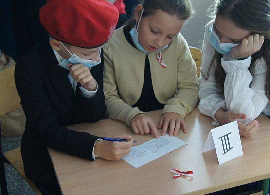 Grupa uczniów wykonuje konkurencyjne zadania na apelu