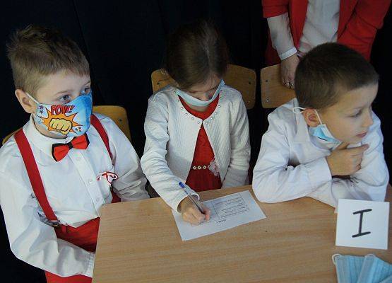 Grupa uczniów wykonuje konkurencyjne zadania na apelu